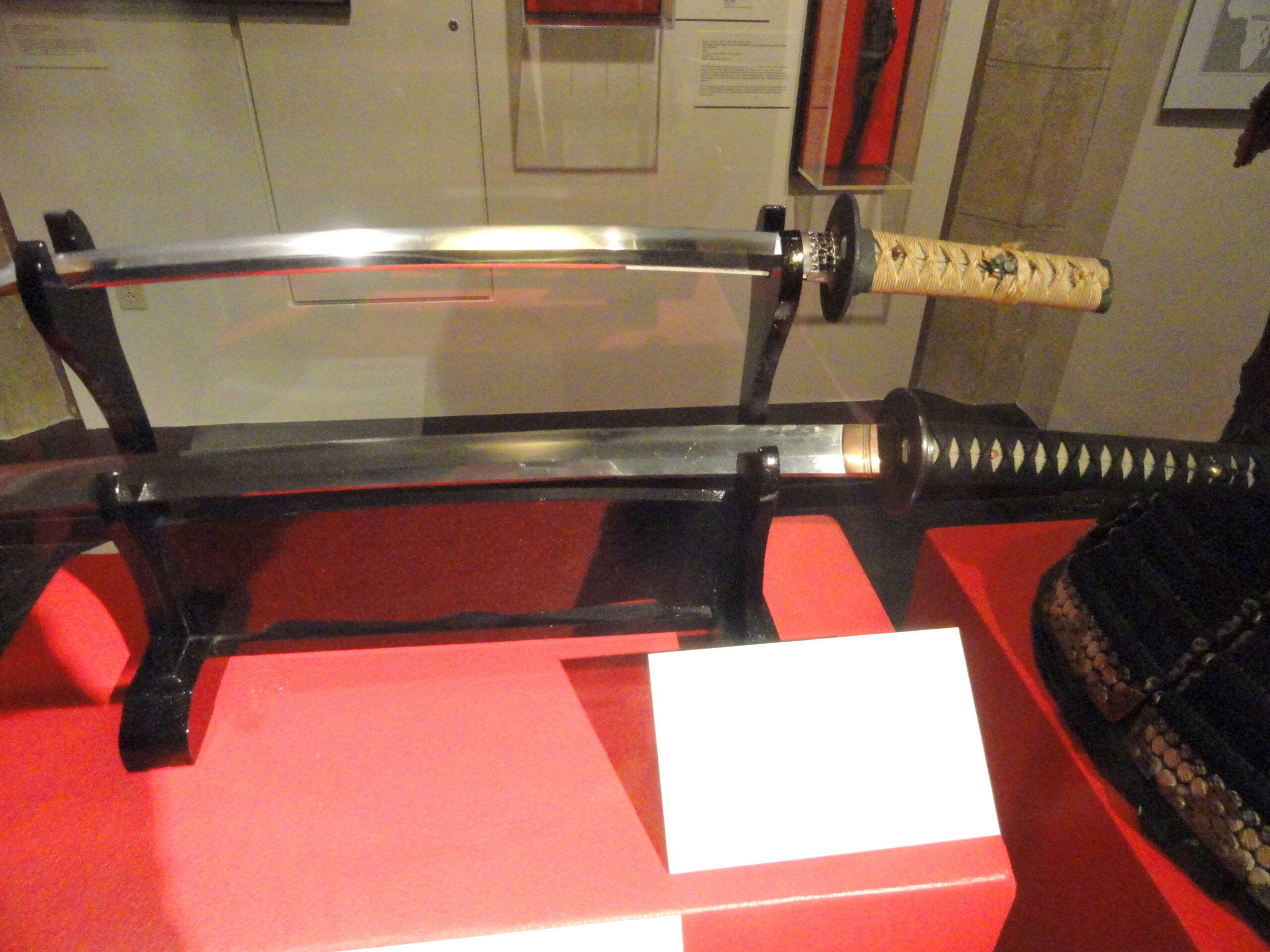 Mehrere japanische Schwerter werden auf horizontalen Museumsregalen im Higgins Armory Museum ausgestellt und zeigen Katana, Wakizashi und Tachi aus verschiedenen Epochen