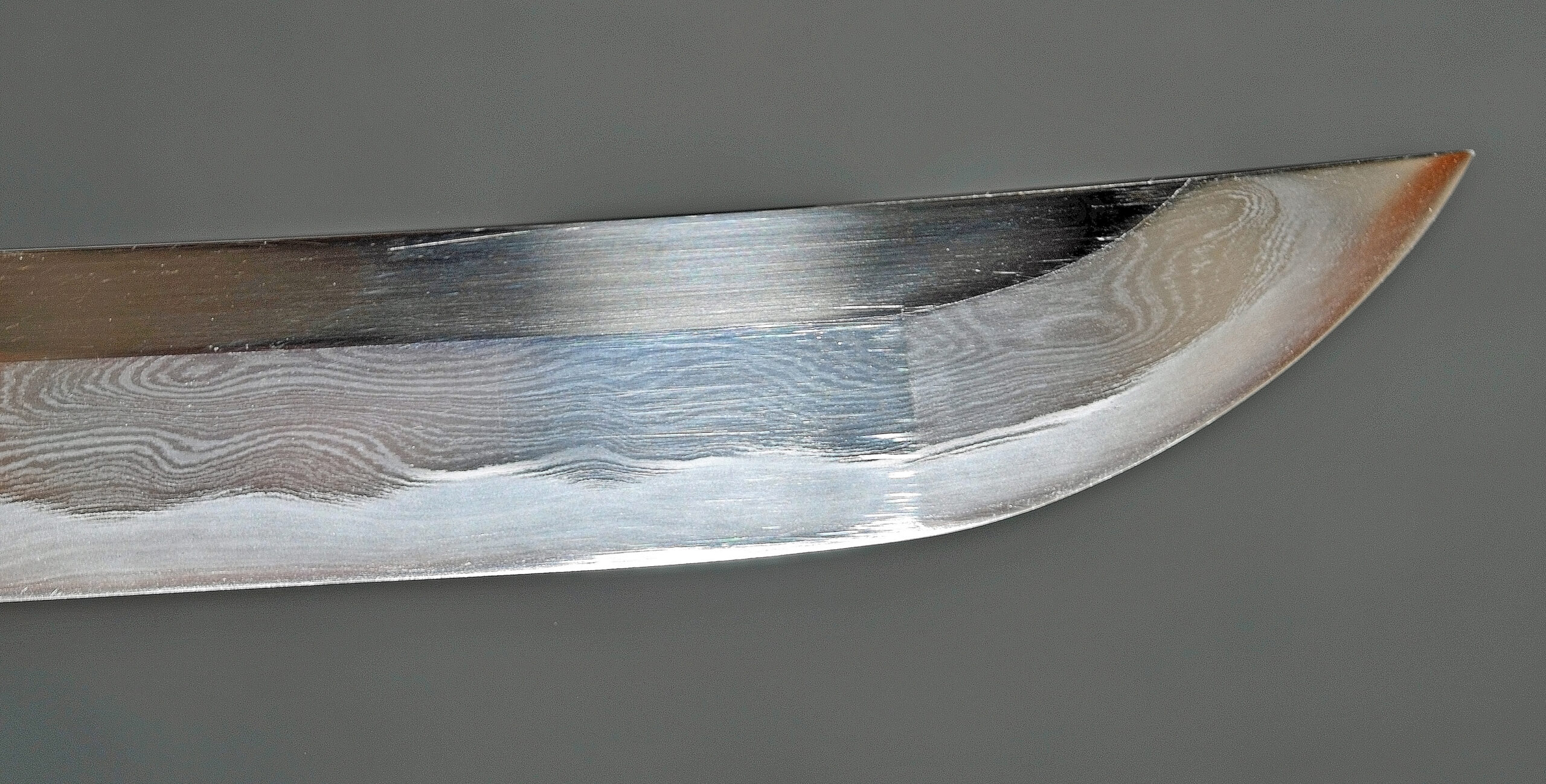 Nahaufnahme einer Katana-Klingenspitze mit Kissaki-Spitze, Hamon-Stärkelinie und Boshi-Muster auf einem gut gepflegten poliertes japanisches Schwert