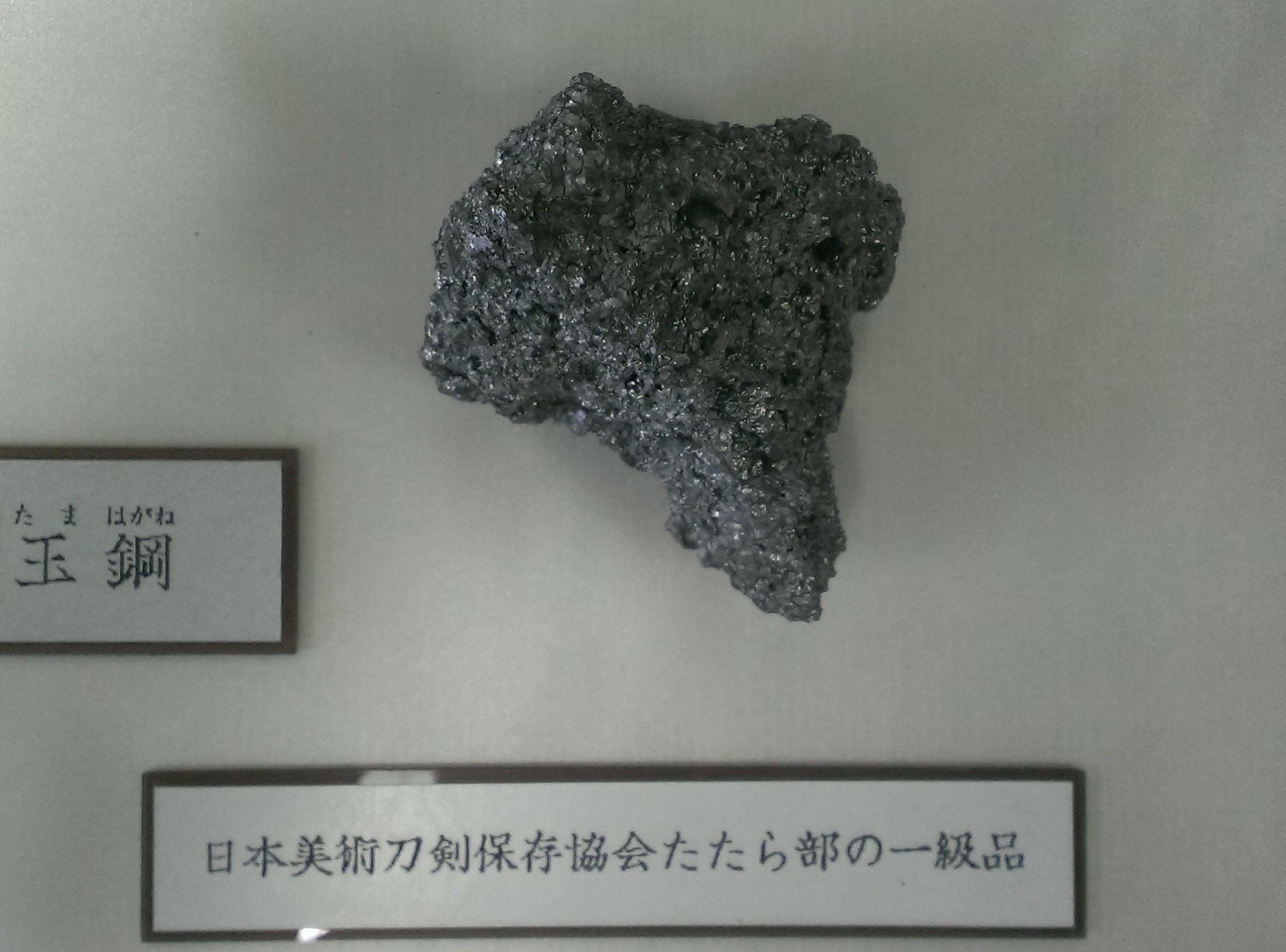 Eine gebrochene Tamahagane-Stahlblüte, die die kristalline Kohlenstoffstruktur zeigt, die zur Bewertung der Qualität japanischer Schwertschmiedearbeiten verwendet wird